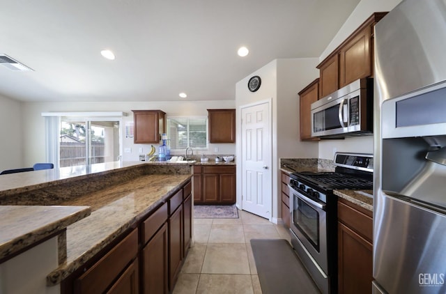 7215 Pine Flat Dr, Bakersfield, CA 93311 - kitchen with appliances with stainless steel finishes, dark stone counters, light tile patterned floors, healthy amount of natural light, and recessed lighting
