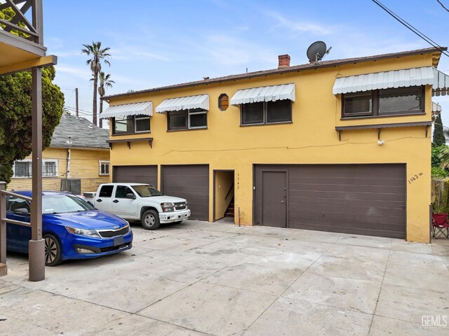 1940 S La Salle Ave, Los Angeles, CA 90018 - view of front facade with an attached garage, stucco siding, concrete driveway, and a chimney