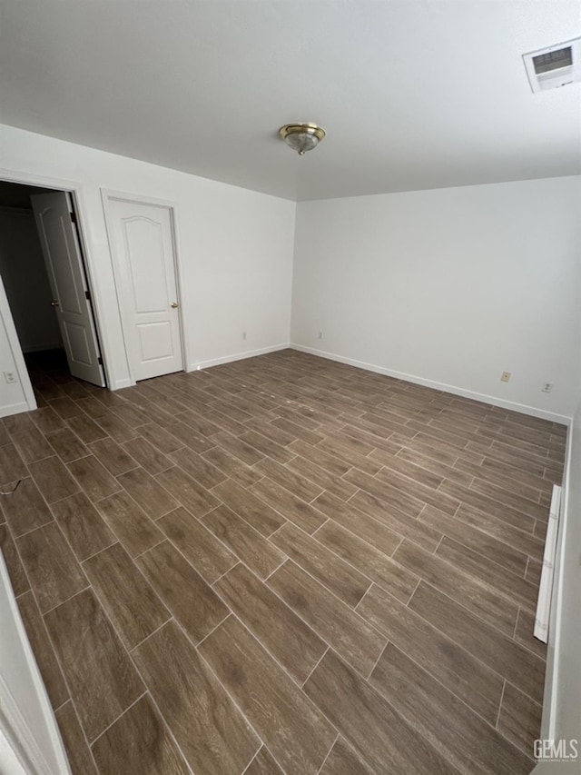 spare room with dark wood-style flooring, baseboards, and visible vents