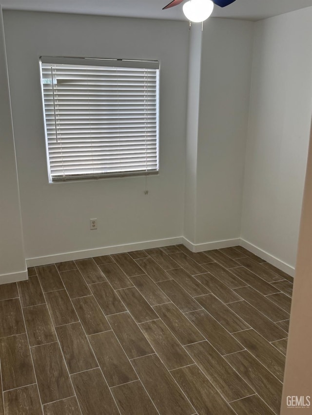 spare room with dark wood finished floors, baseboards, and ceiling fan