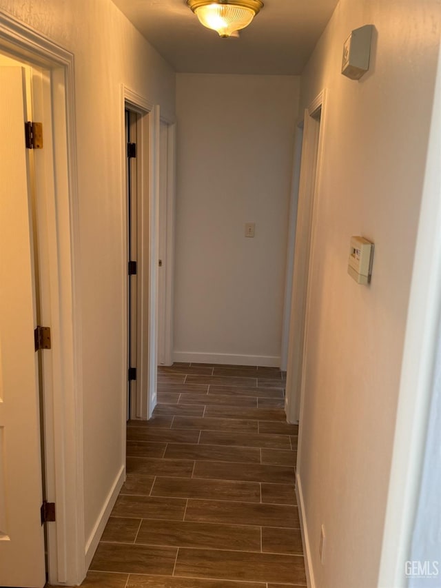 hall featuring baseboards and dark wood-style floors