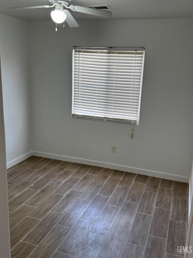 empty room featuring a ceiling fan, baseboards, dark wood-style floors, and visible vents