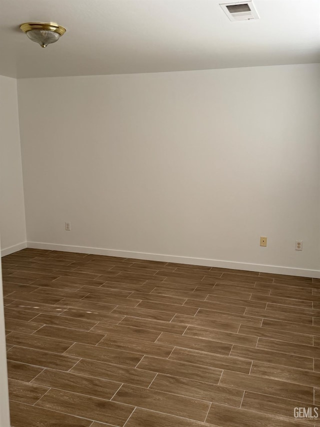 empty room featuring visible vents, baseboards, and dark wood-style floors