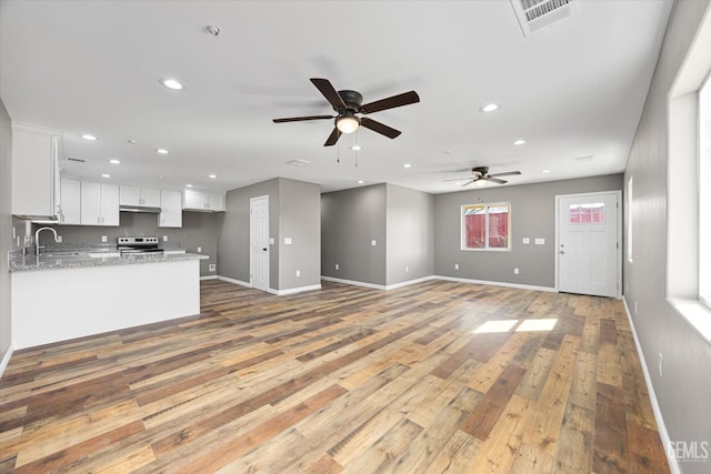 kitchen featuring recessed lighting, light wood-style flooring, white cabinets, a peninsula, and stainless steel electric range