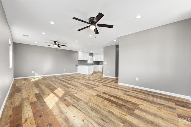 unfurnished living room with light wood-type flooring, visible vents, baseboards, and recessed lighting