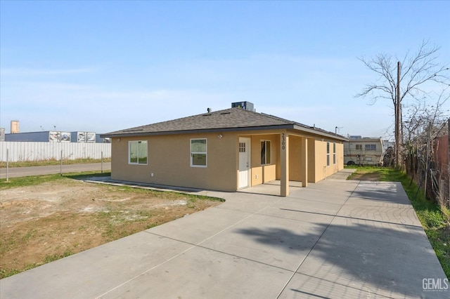 rear view of property with stucco siding, a shingled roof, a patio area, fence, and cooling unit