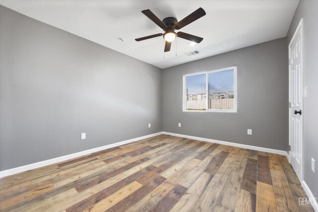 unfurnished room featuring baseboards, ceiling fan, visible vents, and hardwood / wood-style floors