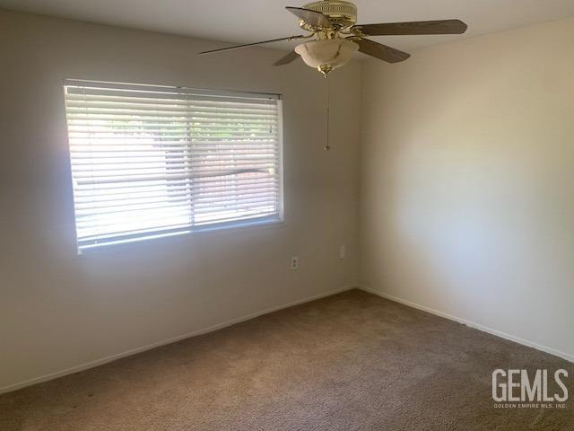 empty room featuring a ceiling fan and carpet