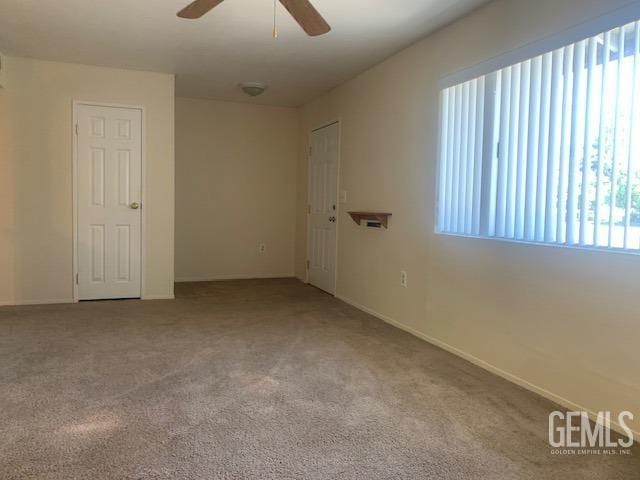 unfurnished room featuring carpet flooring, baseboards, and ceiling fan