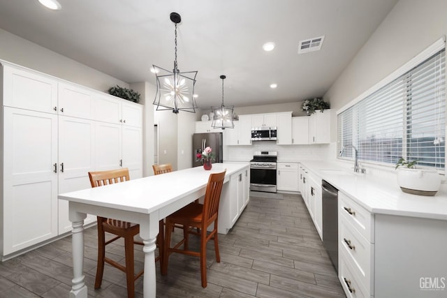 kitchen with stainless steel appliances, a sink, visible vents, white cabinets, and light countertops