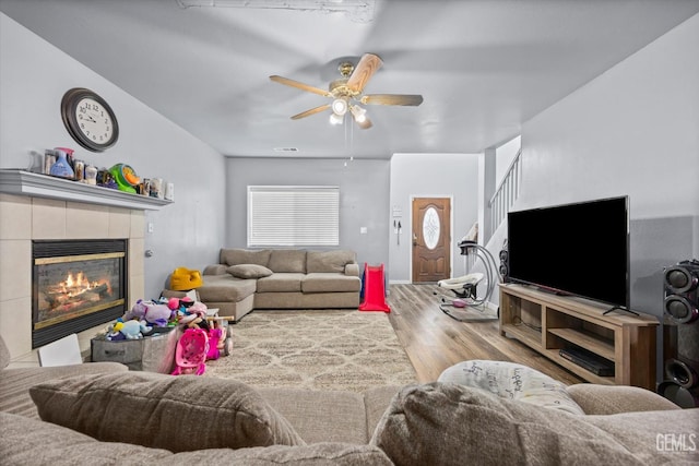 437 Rian Noelle Ct, Bakersfield, CA 93308 - living room featuring wood finished floors, a tiled fireplace, a ceiling fan, and stairway