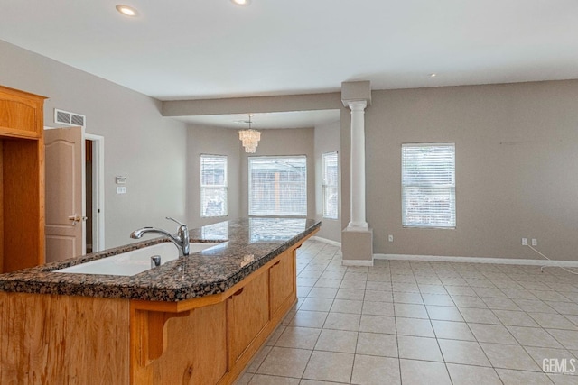 kitchen featuring decorative columns, light tile patterned flooring, visible vents, and a sink