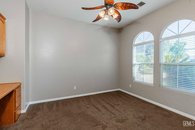 unfurnished room with dark colored carpet, visible vents, baseboards, and ceiling fan