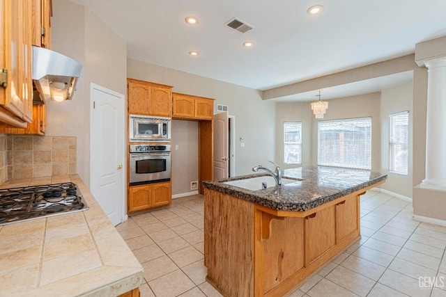 kitchen featuring visible vents, a sink, range hood, stainless steel appliances, and ornate columns