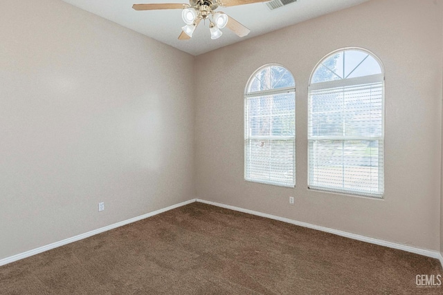 empty room with visible vents, baseboards, a ceiling fan, and dark carpet