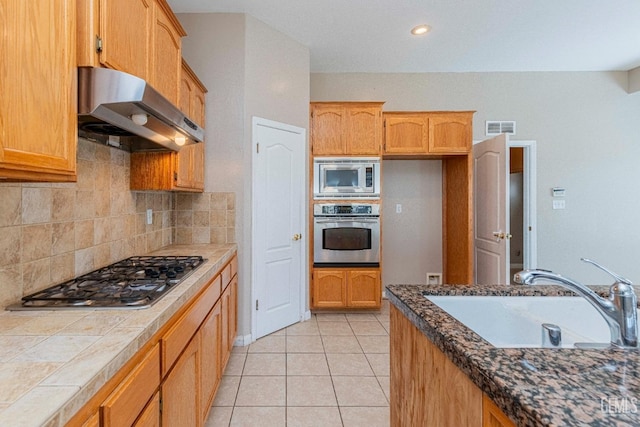 kitchen featuring visible vents, ventilation hood, appliances with stainless steel finishes, light tile patterned flooring, and a sink