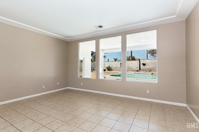 spare room featuring light tile patterned floors, visible vents, and baseboards