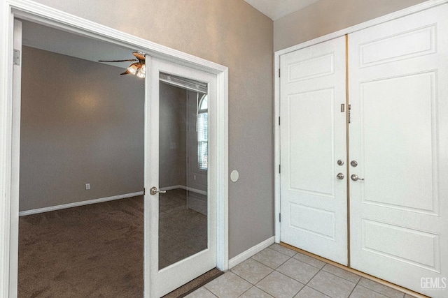 foyer entrance with light tile patterned floors, french doors, baseboards, and a ceiling fan