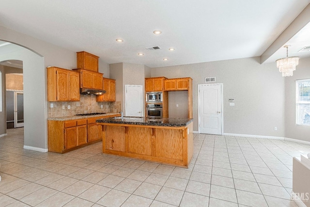 kitchen featuring under cabinet range hood, visible vents, arched walkways, and appliances with stainless steel finishes