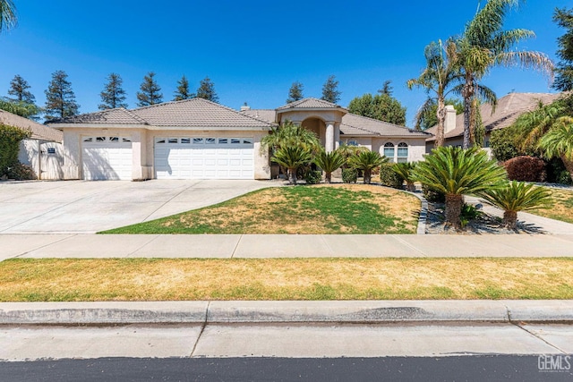 mediterranean / spanish-style home featuring a front yard, an attached garage, stucco siding, concrete driveway, and a tile roof