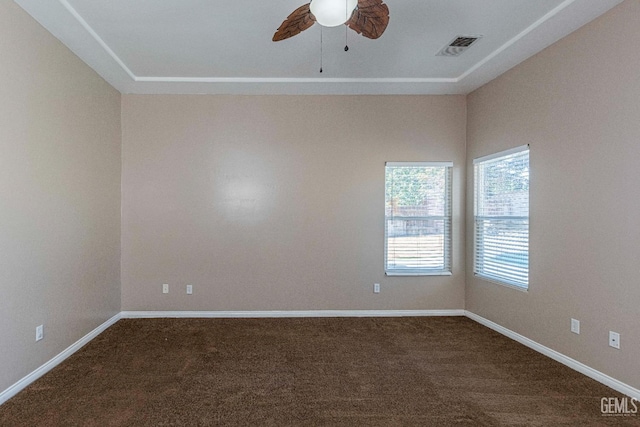 spare room featuring visible vents, dark carpet, baseboards, and ceiling fan