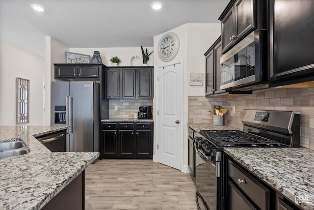 9008 Pine Breeze Ln, Shafter, CA 93263 - kitchen featuring light stone counters, stainless steel appliances, recessed lighting, decorative backsplash, and light wood-type flooring