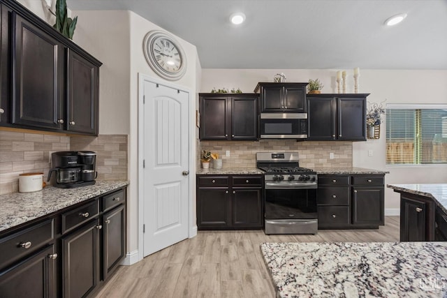 9008 Pine Breeze Ln, Shafter, CA 93263 - kitchen featuring appliances with stainless steel finishes, tasteful backsplash, light stone countertops, and light wood-type flooring