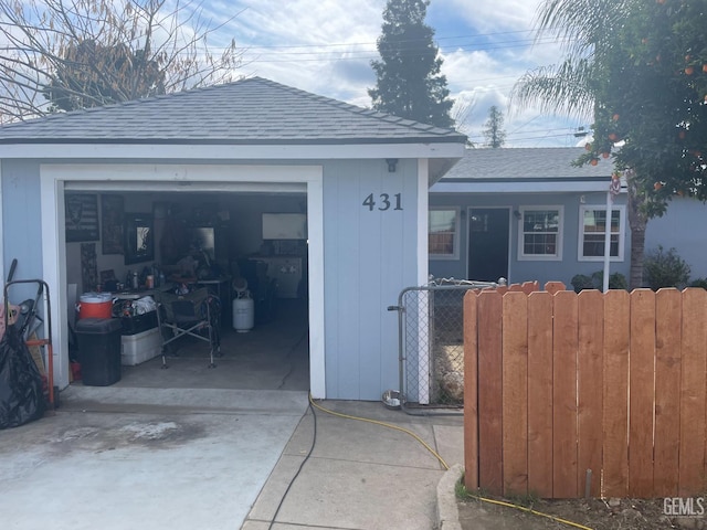 garage with concrete driveway and fence