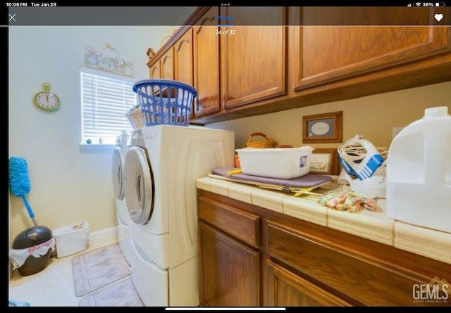 clothes washing area featuring light tile patterned floors, cabinets, and washing machine and clothes dryer