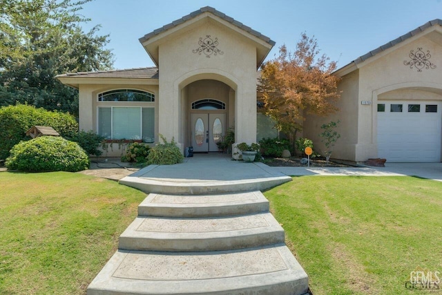 view of exterior entry with french doors, a garage, and a yard