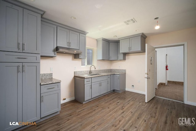 428 Center St Unit A, Taft, CA 93268 - kitchen with gray cabinets, under cabinet range hood, wood finished floors, recessed lighting, and light stone countertops