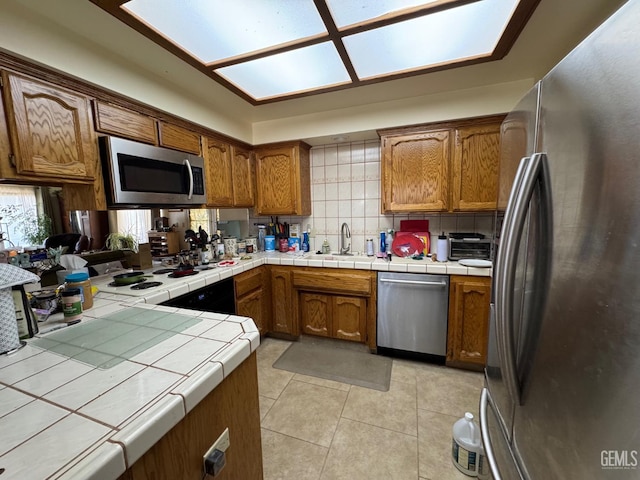 22417 Citation St, Tehachapi, CA 93561 - kitchen featuring appliances with stainless steel finishes, tile counters, and brown cabinetry