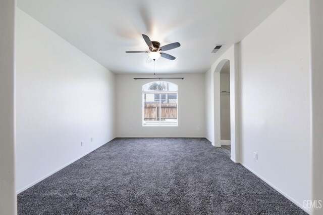 spare room featuring ceiling fan and dark carpet