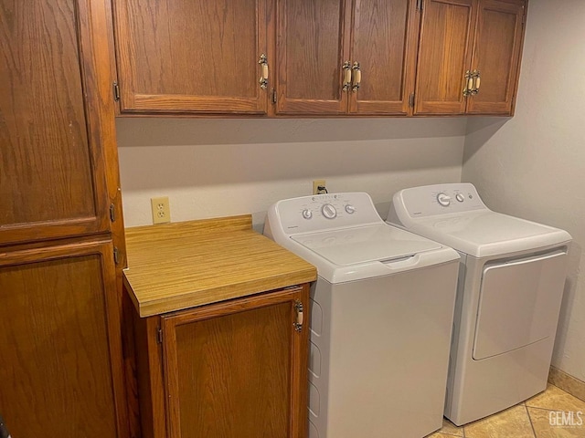 washroom featuring washer and dryer, light tile patterned floors, and cabinet space