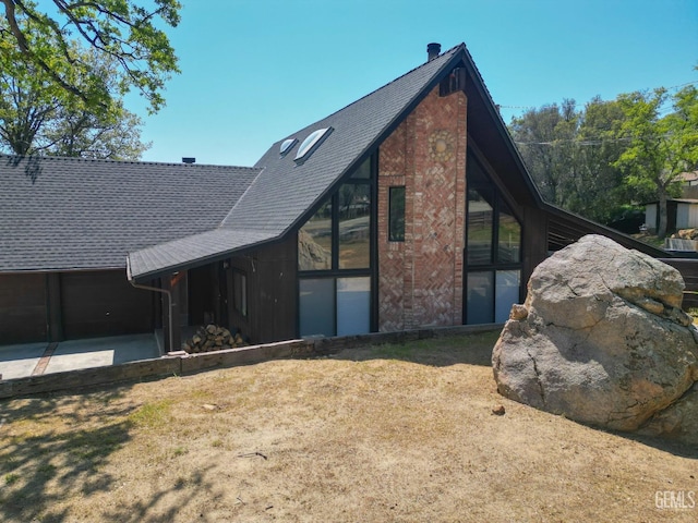 exterior space with a garage, brick siding, and a shingled roof