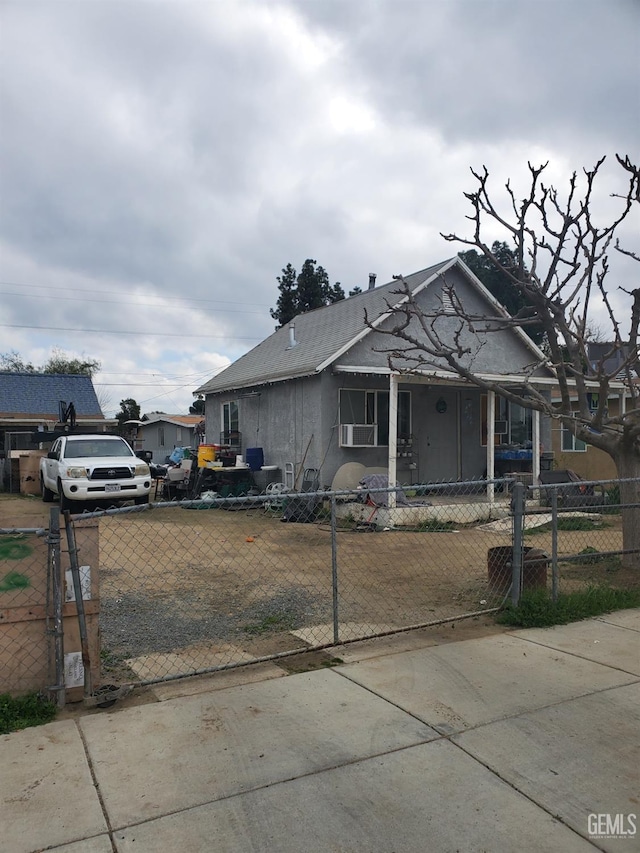 bungalow-style home with a fenced front yard, cooling unit, and stucco siding