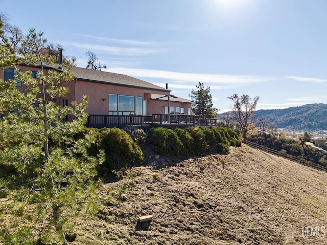 rear view of house with a deck with mountain view and stucco siding