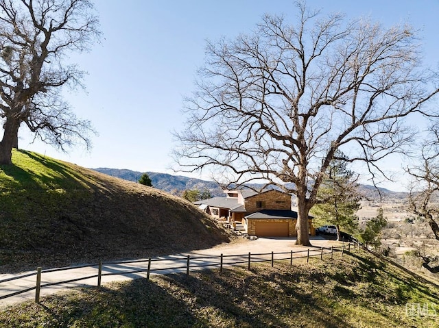 view of yard featuring driveway, a fenced front yard, and a mountain view