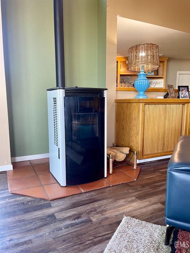 living room with wood finished floors, a wood stove, and baseboards