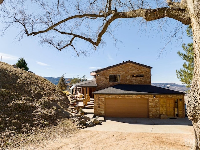 view of front of home with stone siding, driveway, and a mountain view