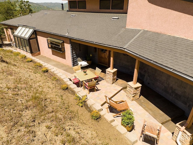 back of house with roof with shingles, a patio, an outdoor hangout area, and stucco siding