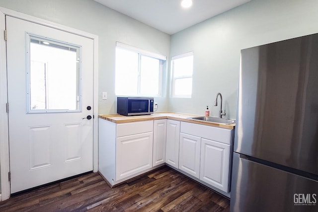 kitchen featuring stainless steel appliances, dark wood-type flooring, a sink, and white cabinetry