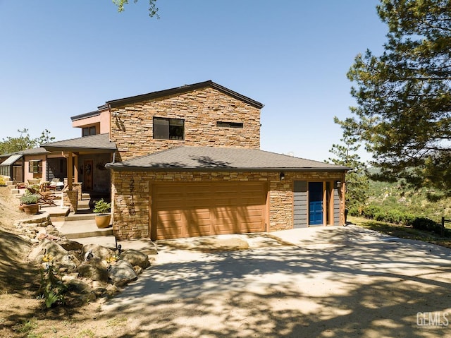 view of front of home featuring driveway, stone siding, and an attached garage