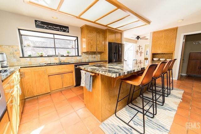 kitchen with dishwashing machine, stone countertops, a sink, refrigerator with ice dispenser, and decorative backsplash