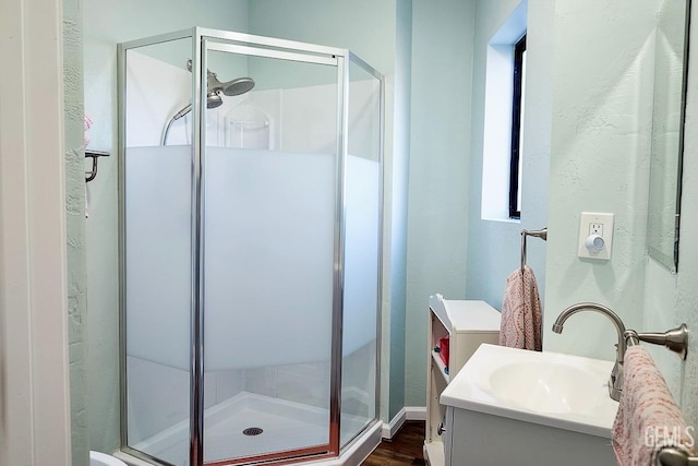 full bath featuring wood finished floors, a shower stall, and vanity