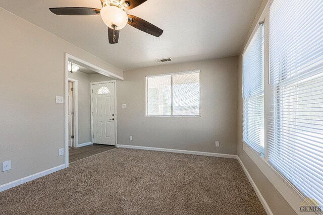 interior space with visible vents, a ceiling fan, baseboards, and dark colored carpet
