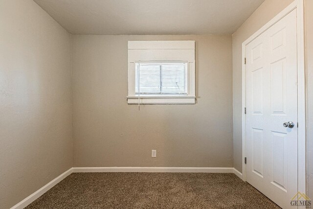 carpeted spare room featuring baseboards
