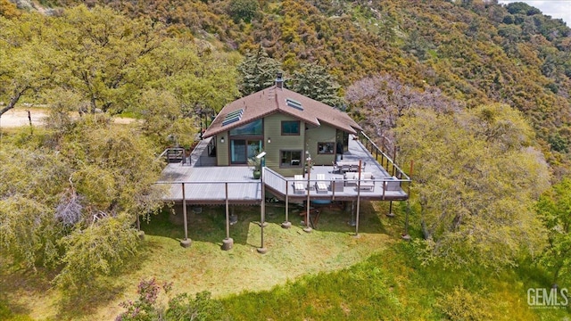 rear view of property featuring a wooden deck and a wooded view