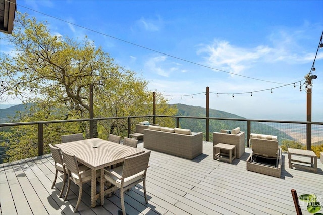 wooden terrace with an outdoor living space, outdoor dining area, and a mountain view