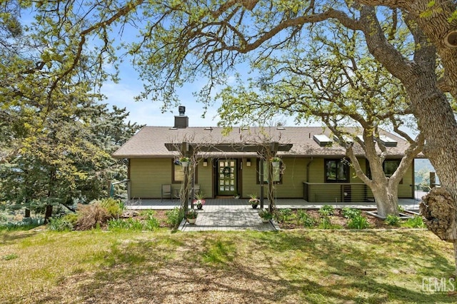 rear view of house with a yard, french doors, and a chimney